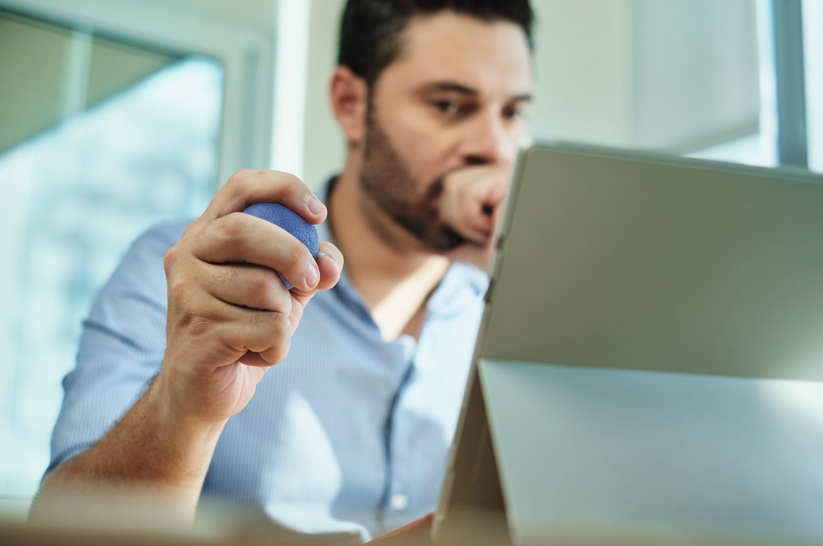 Dorosły mężczyzna w biurze, ściskający piłkę antystresową