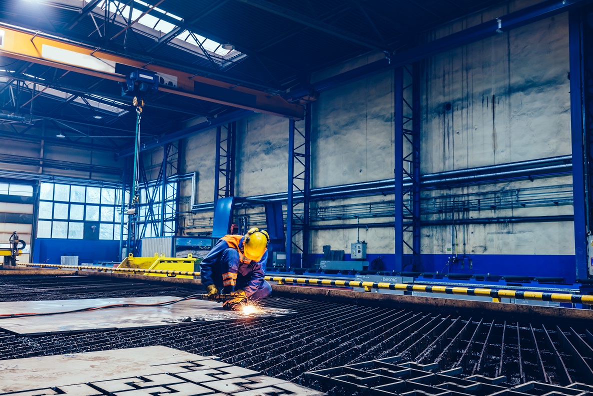 Spawający pracownik w hali stalowej
